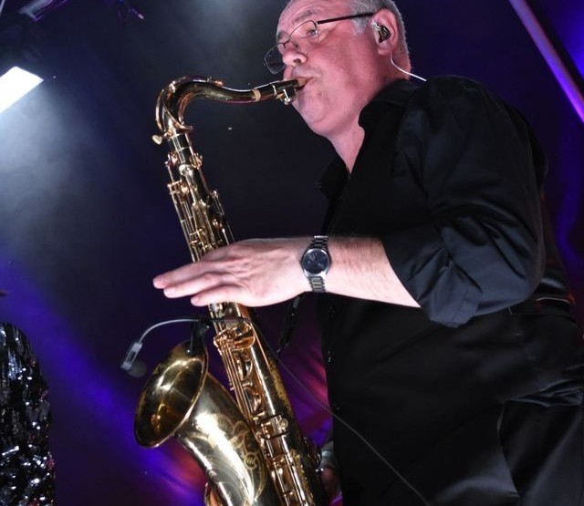The Rolling Clones 11-piece lineup with horn section on a theatre stage