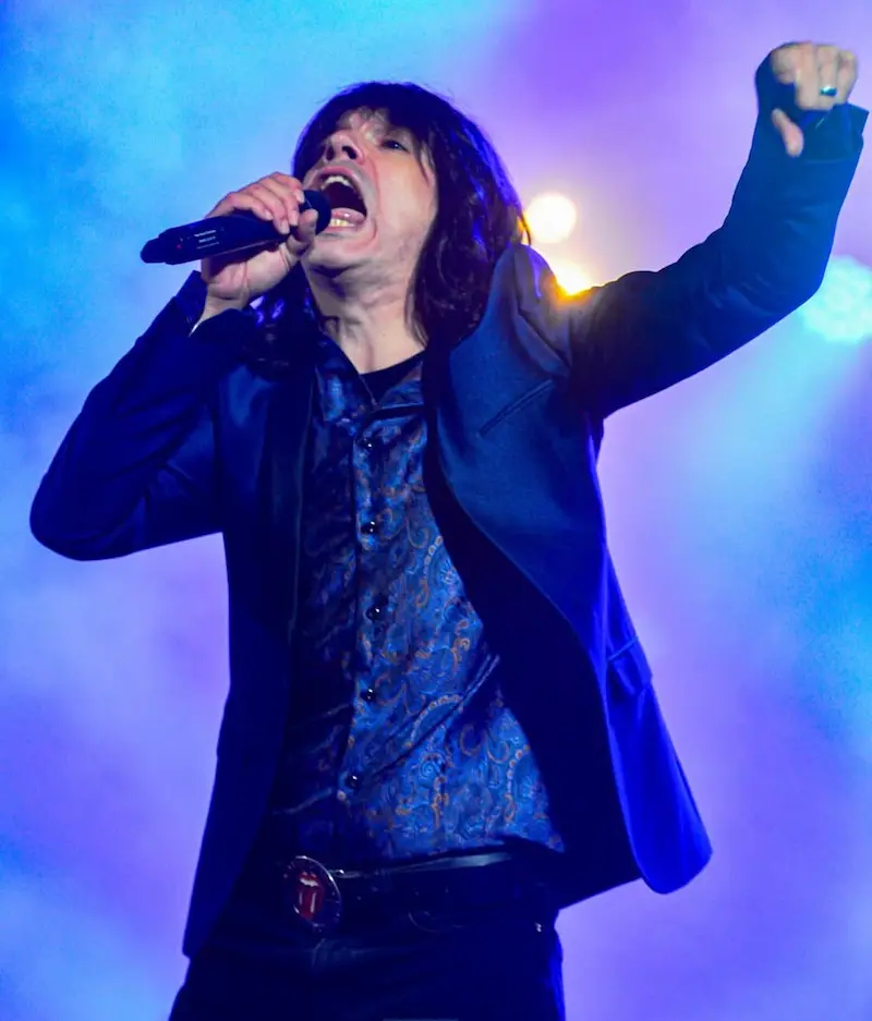 The Rolling Clones on a theatre stage — frontman engaging a seated audience